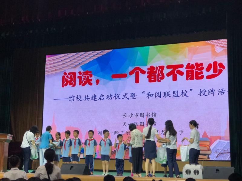 2020年7月8日上午9点,由天心区图书承办的“阅读，一个都不能少”馆校共建活动在天心区龙湾小学体育馆内举行，图为天心区图书馆工作人员上台为小朋友赠送免押金的读者证。.jpg